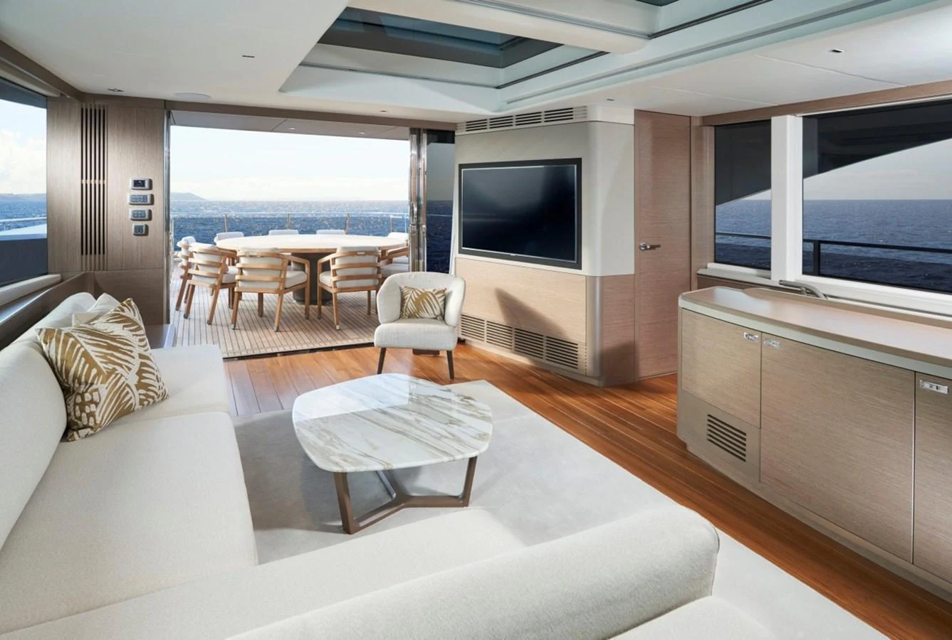 The salon offers a spacious and elegant area with comfortable seating and a large TV, opening to an alfresco dining area with stunning sea views. aboard OCEAN THREE Yacht for Sale