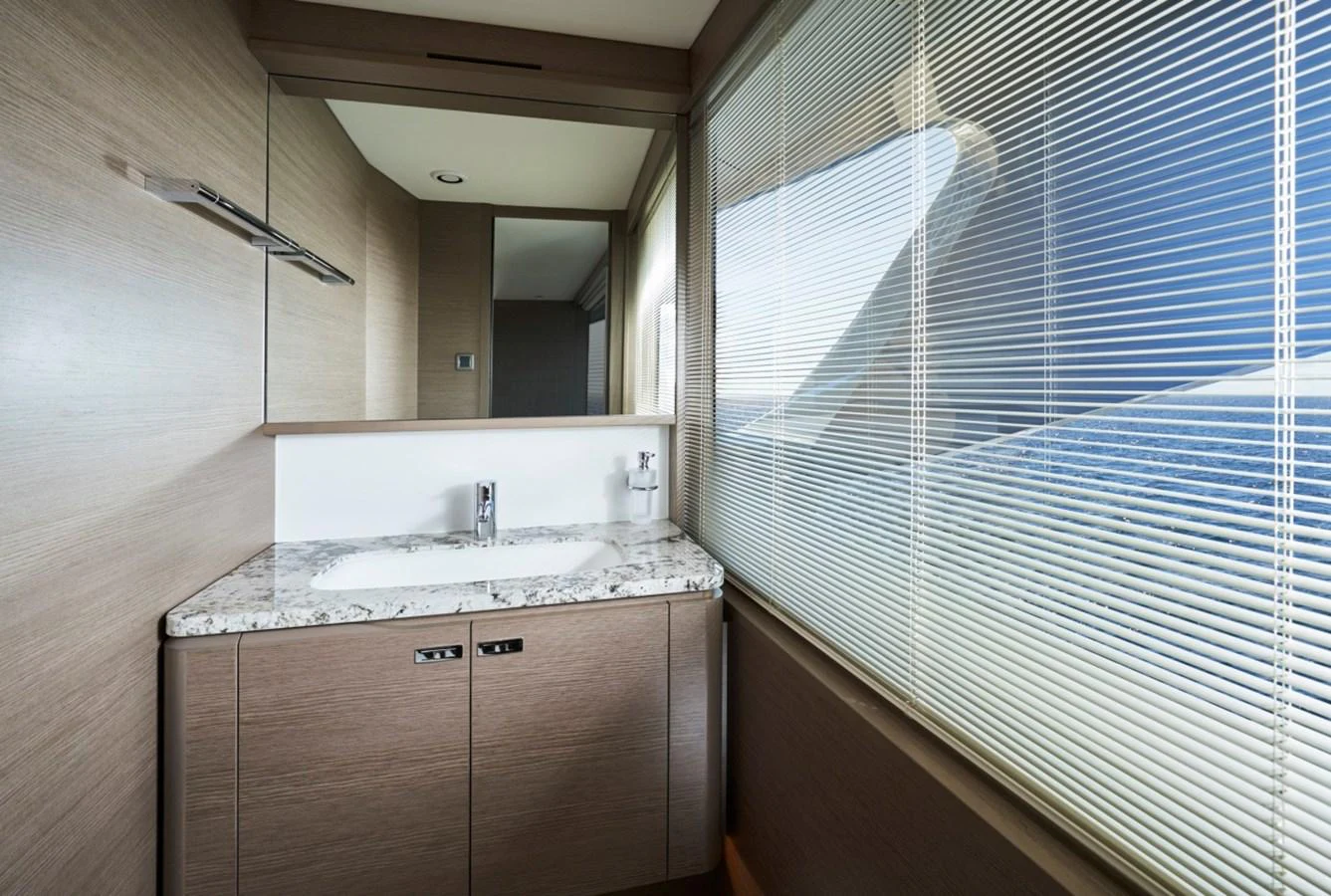 The yacht's bathroom features a sleek design with a marble countertop and large window blinds. aboard OCEAN THREE Yacht for Sale