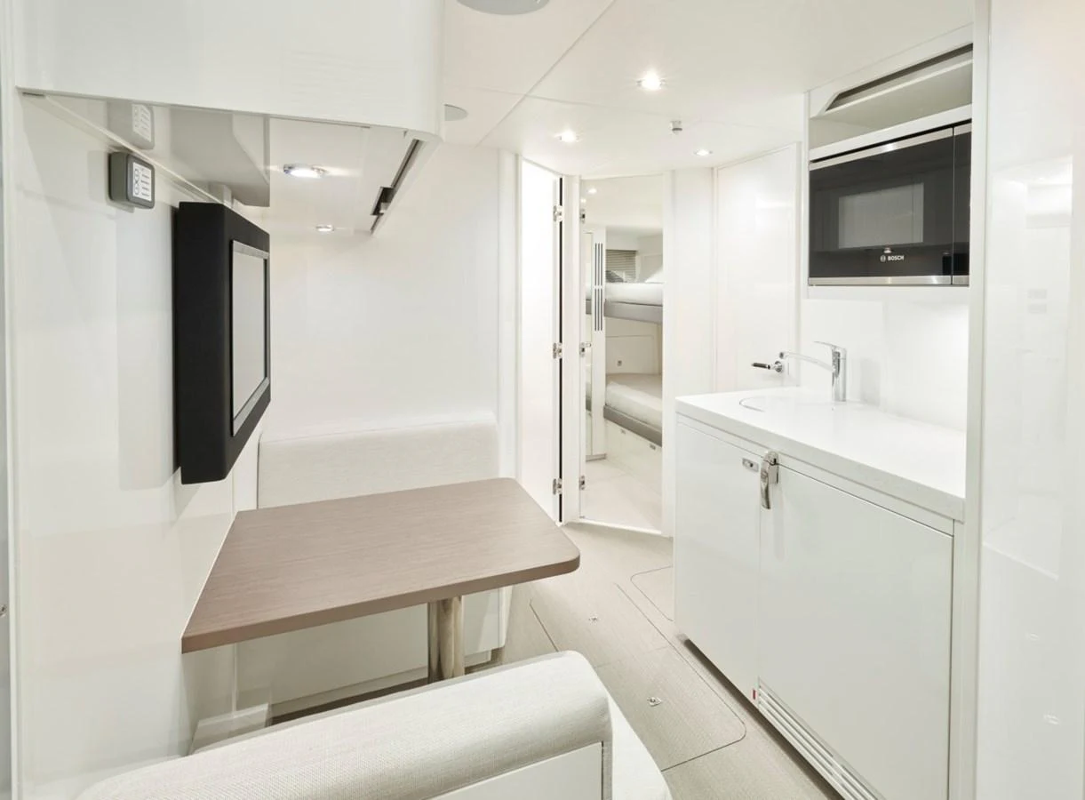 The yacht's galley features a sleek, modern design with a compact dining area and integrated appliances. aboard OCEAN THREE Yacht for Sale
