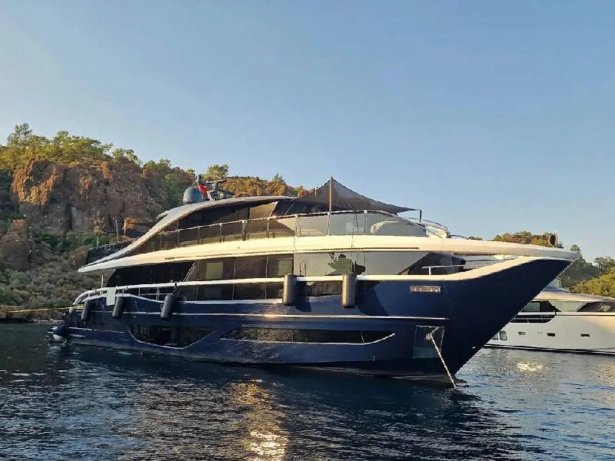 A sleek and modern yacht is anchored in a serene coastal area, showcasing its elegant design and spacious decks. aboard OCEAN THREE Yacht for Sale
