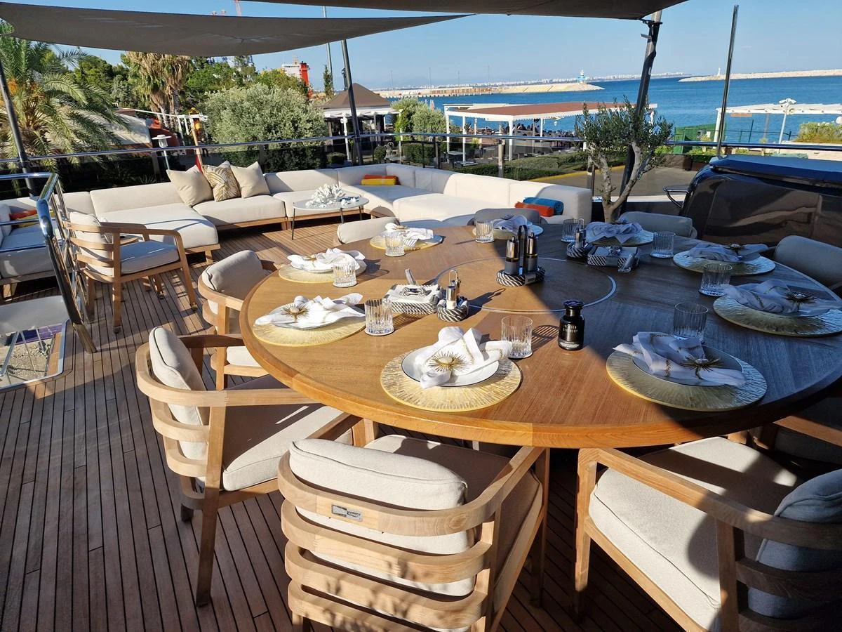 The aft deck features a spacious dining area with a large round table and comfortable seating, perfect for alfresco dining. aboard OCEAN THREE Yacht for Sale