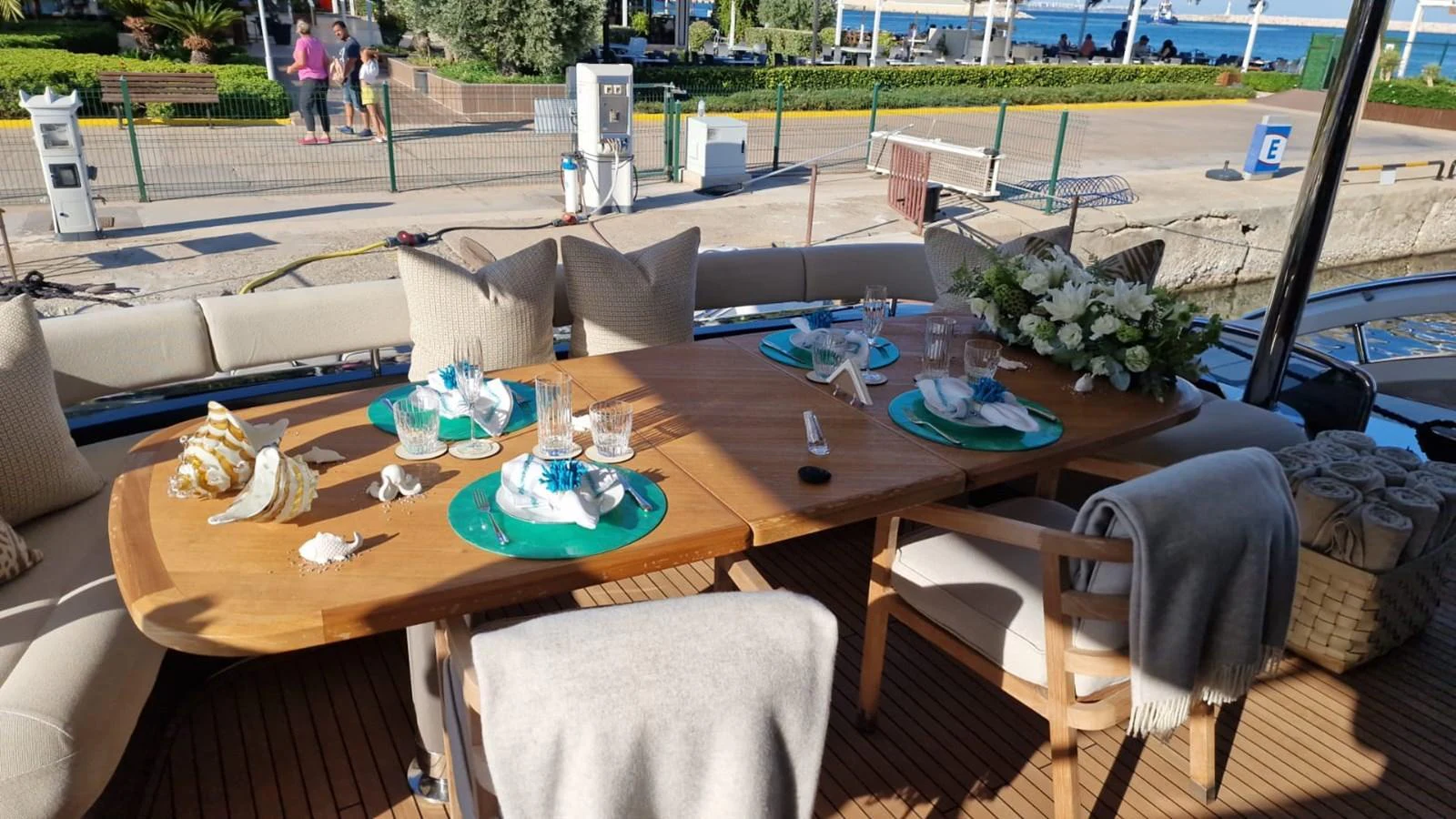 The aft deck features an elegant dining area with a wooden table set for a meal, surrounded by comfortable seating and adorned with decorative elements. aboard OCEAN THREE Yacht for Sale