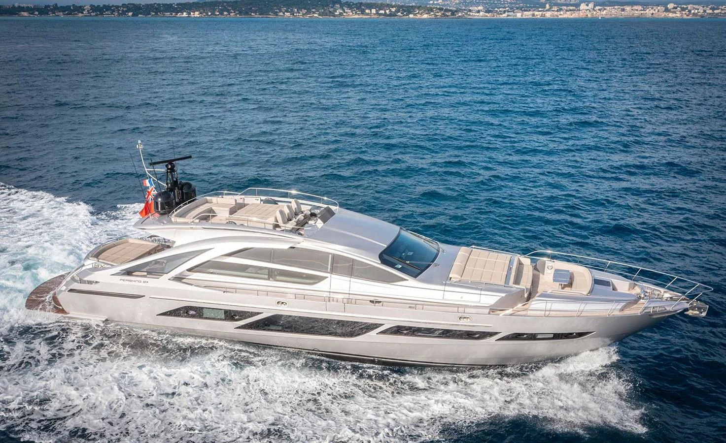 A sleek and modern yacht cruising on the open water with a stunning coastal backdrop. aboard MAGIC OF AYR Yacht for Sale