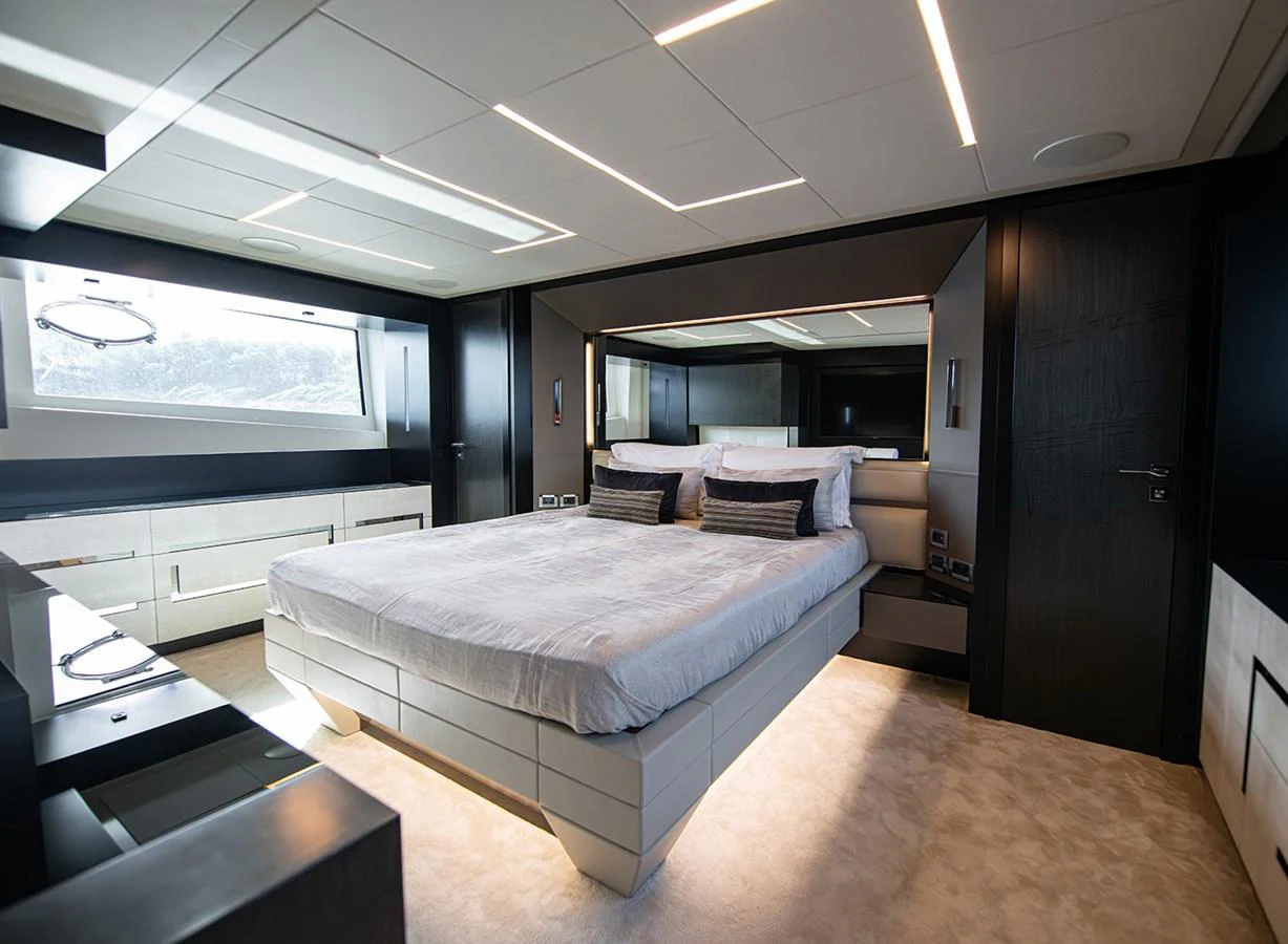 The master stateroom features a luxurious bed with modern lighting and ample natural light from the large window. aboard MAGIC OF AYR Yacht for Sale