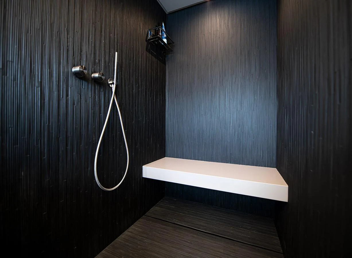 A sleek and modern shower area with dark textured walls and a minimalist design. aboard MAGIC OF AYR Yacht for Sale