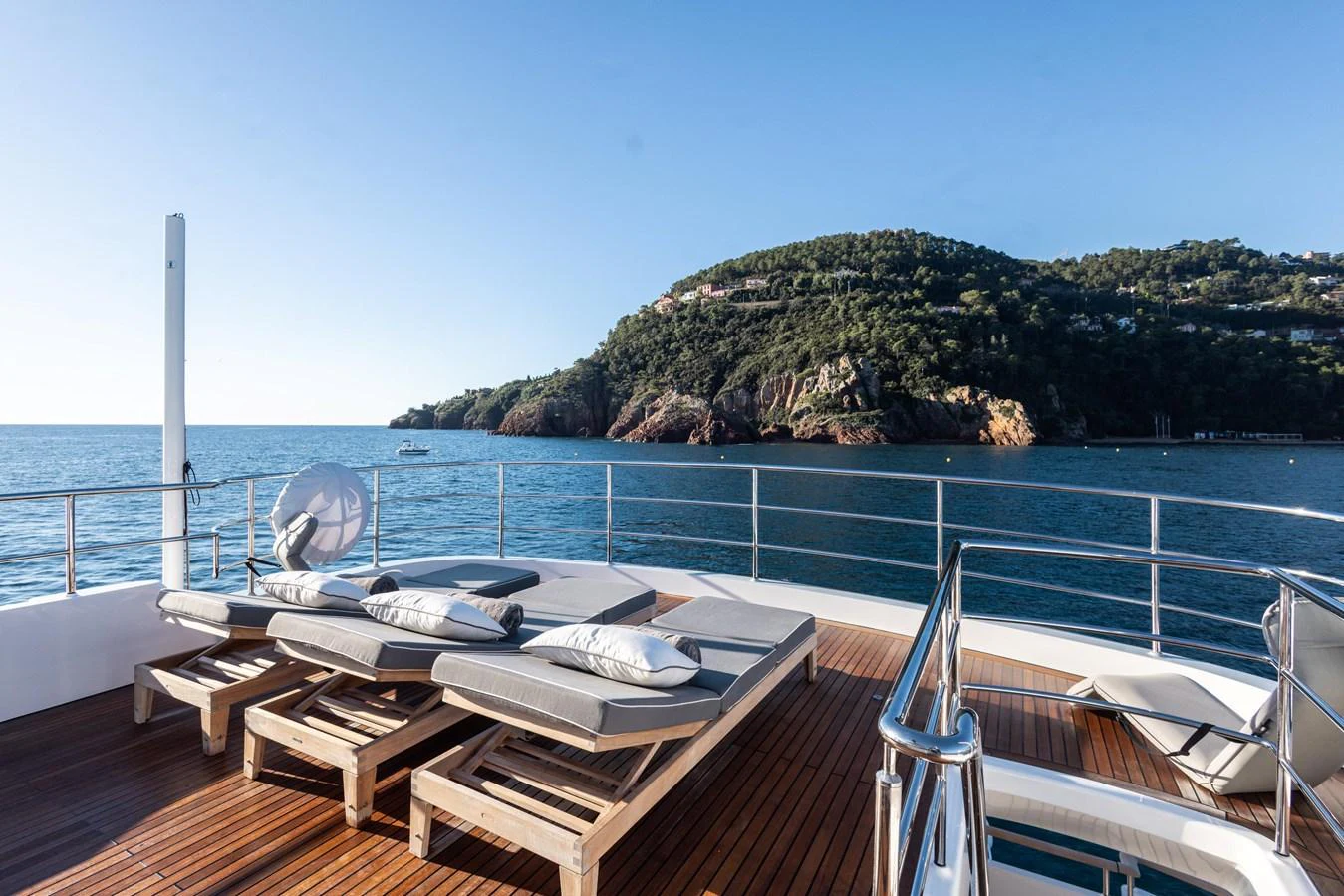 a deck with a view of a beach and trees aboard ARCHIPELAGO Yacht for Sale