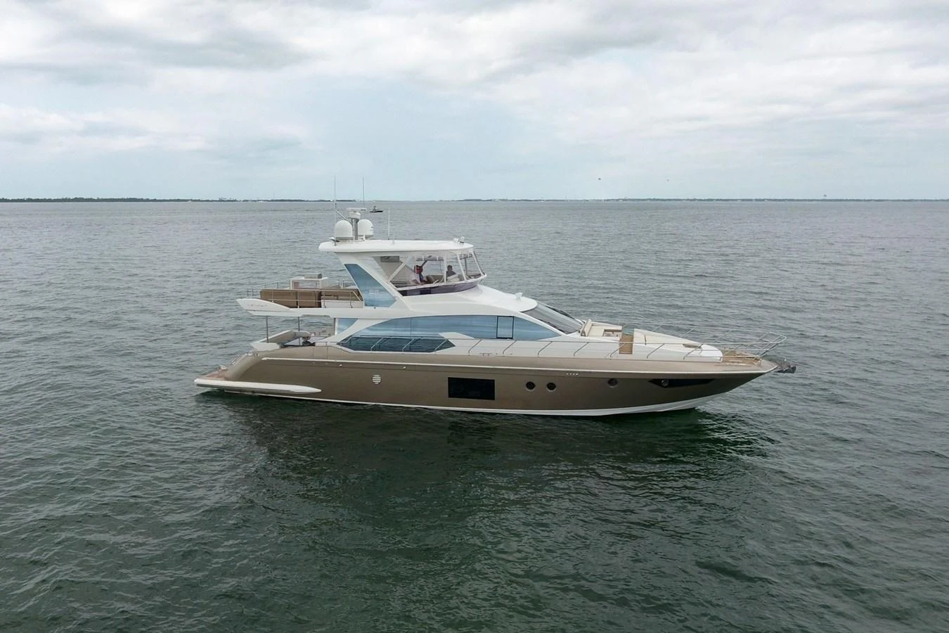 A sleek and modern yacht cruising on calm waters under a cloudy sky. aboard KIKI Yacht for Sale