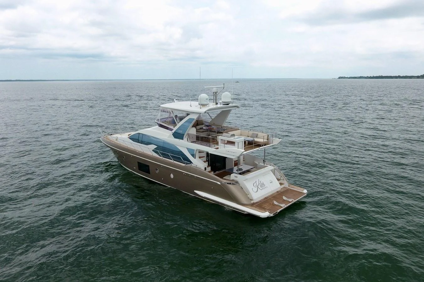 A luxurious yacht cruising on calm waters under a cloudy sky. aboard KIKI Yacht for Sale