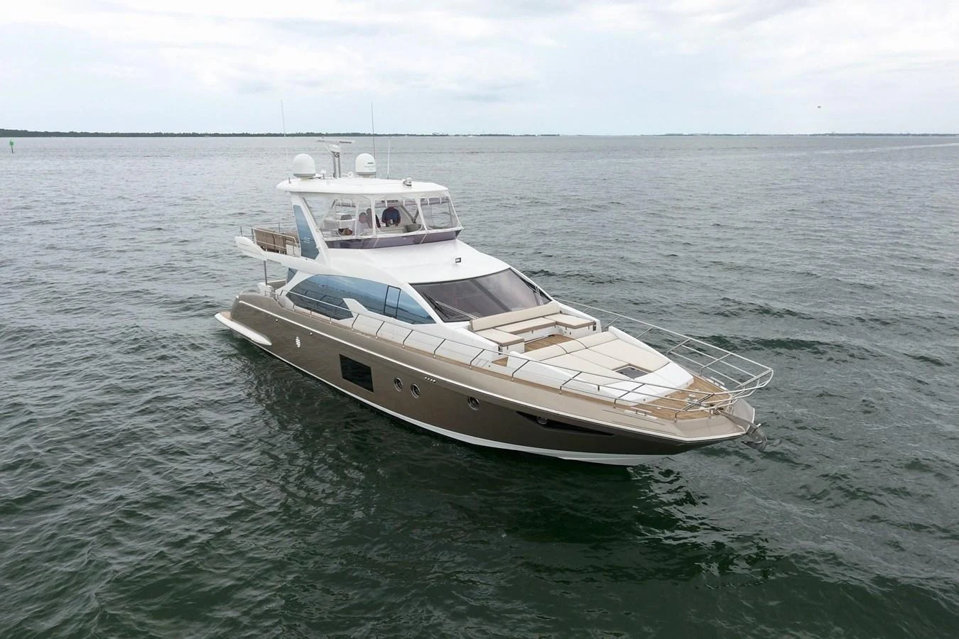 A sleek and modern yacht cruising on calm waters under a cloudy sky. aboard KIKI Yacht for Sale