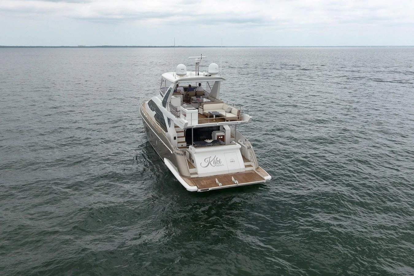 A sleek yacht cruises on calm waters, showcasing its spacious aft deck and elegant design. aboard KIKI Yacht for Sale