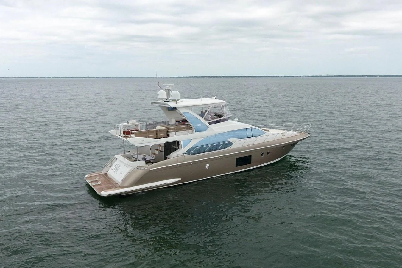 A sleek and modern yacht cruising on calm waters under a cloudy sky. aboard KIKI Yacht for Sale