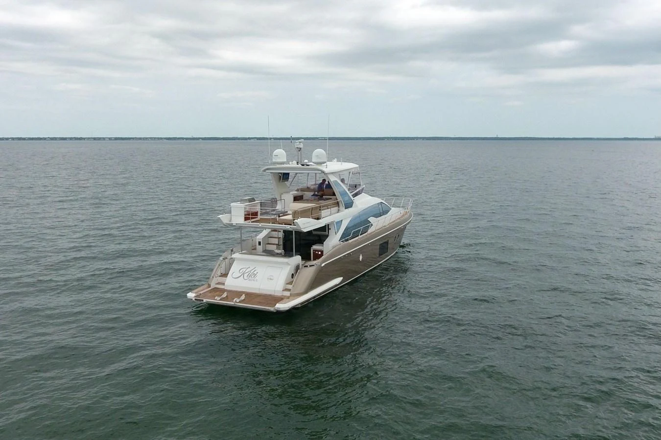 A sleek yacht cruises on calm waters under a cloudy sky. aboard KIKI Yacht for Sale