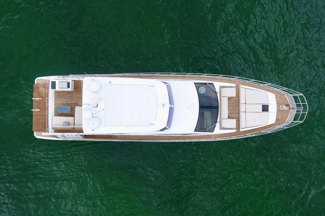 An aerial view of a sleek yacht cruising through calm green waters. aboard KIKI Yacht for Sale