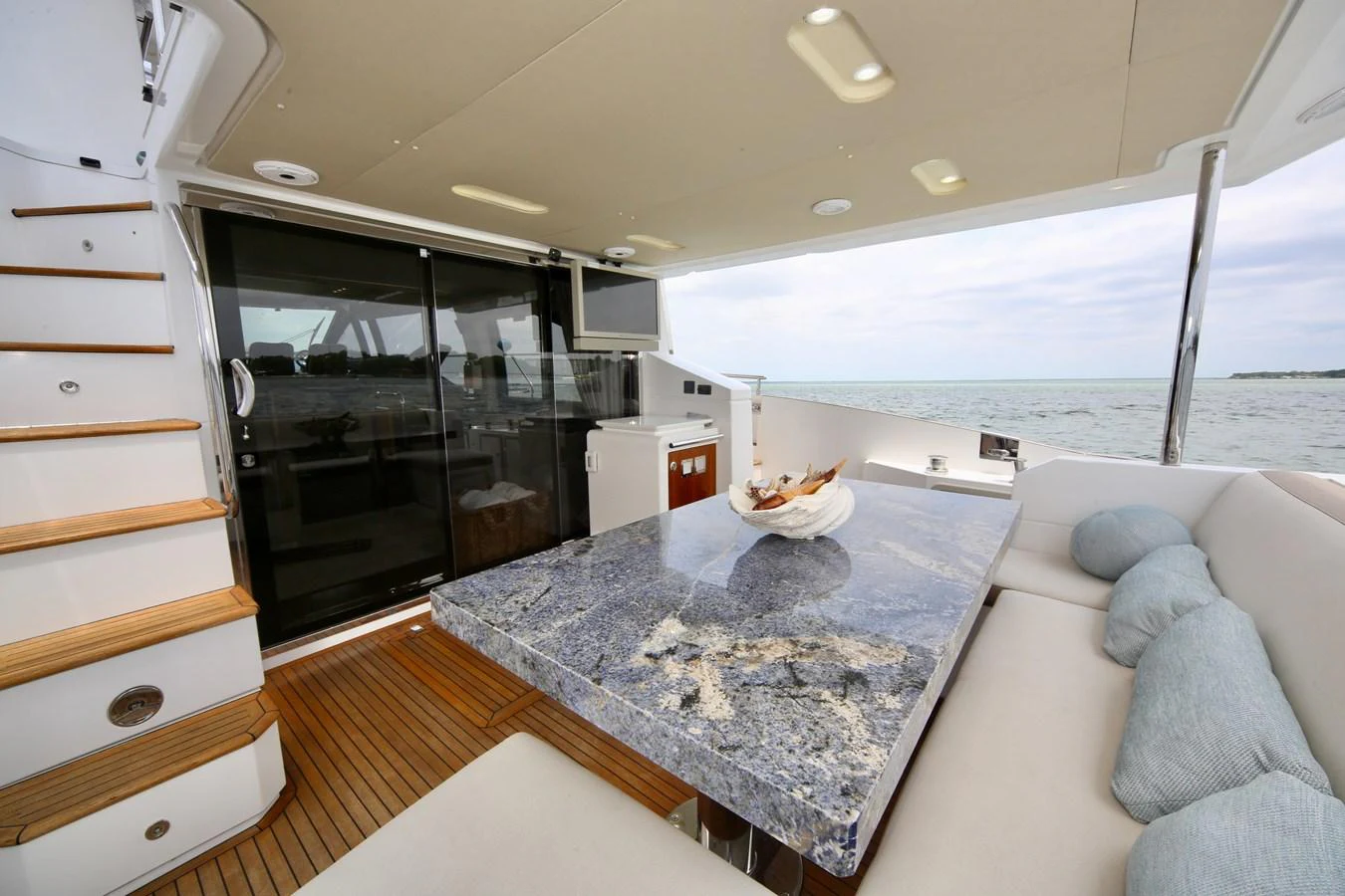 The aft deck features a luxurious dining area with a stunning stone table and comfortable seating, perfect for alfresco meals with a view. aboard KIKI Yacht for Sale