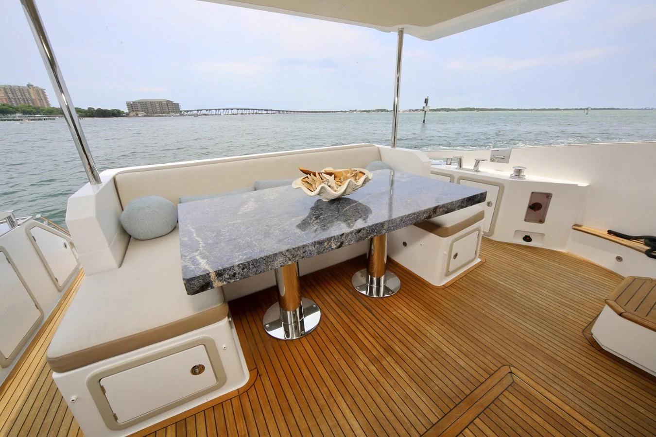 The aft deck features a luxurious dining area with a marble table and comfortable seating, offering stunning views of the water. aboard KIKI Yacht for Sale