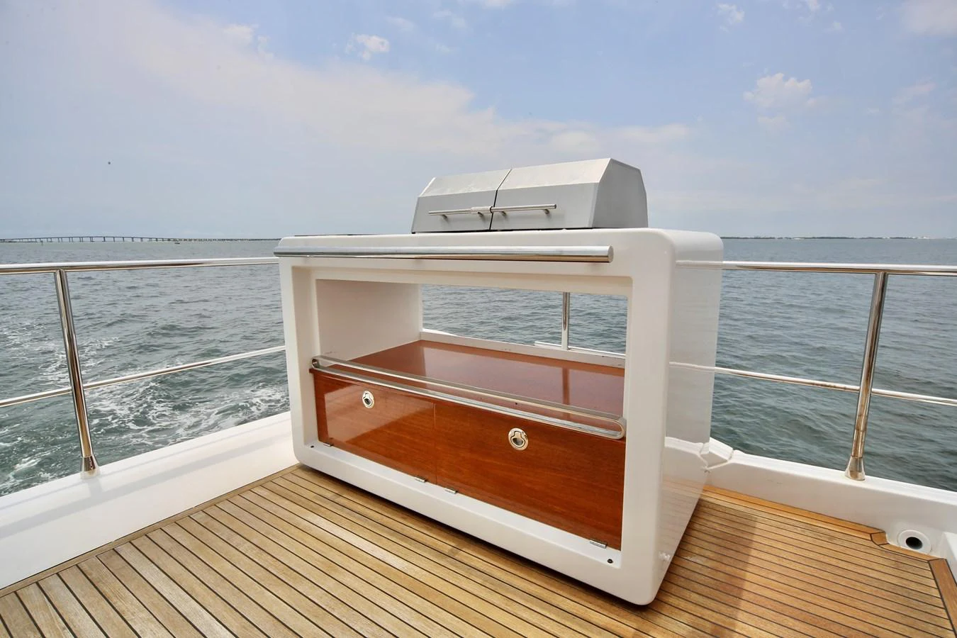 The aft deck features a sleek outdoor grill station with a wooden cabinet and stainless steel accents. aboard KIKI Yacht for Sale