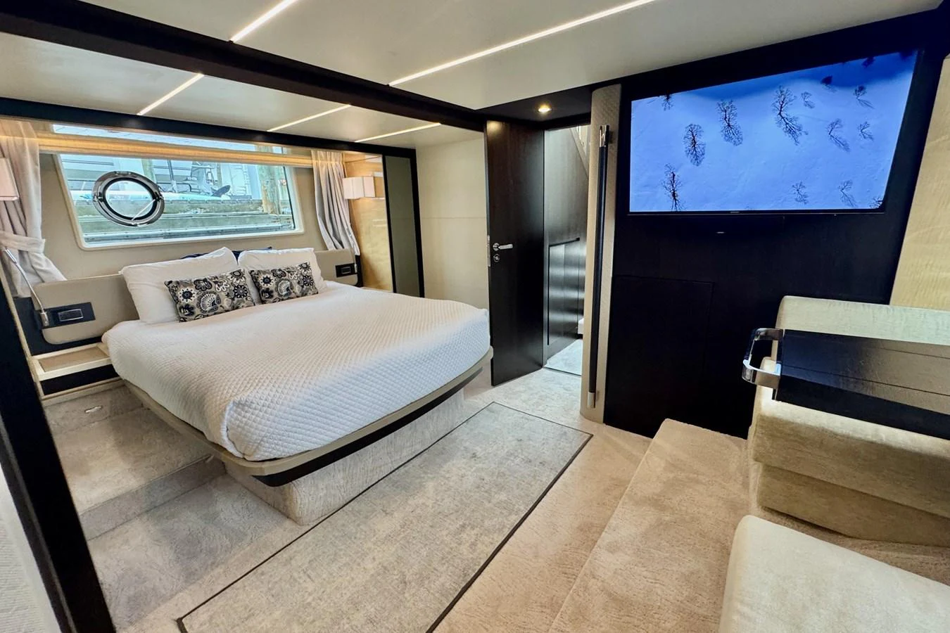 A luxurious stateroom with a comfortable bed, modern decor, and a large window providing natural light. aboard KIKI Yacht for Sale