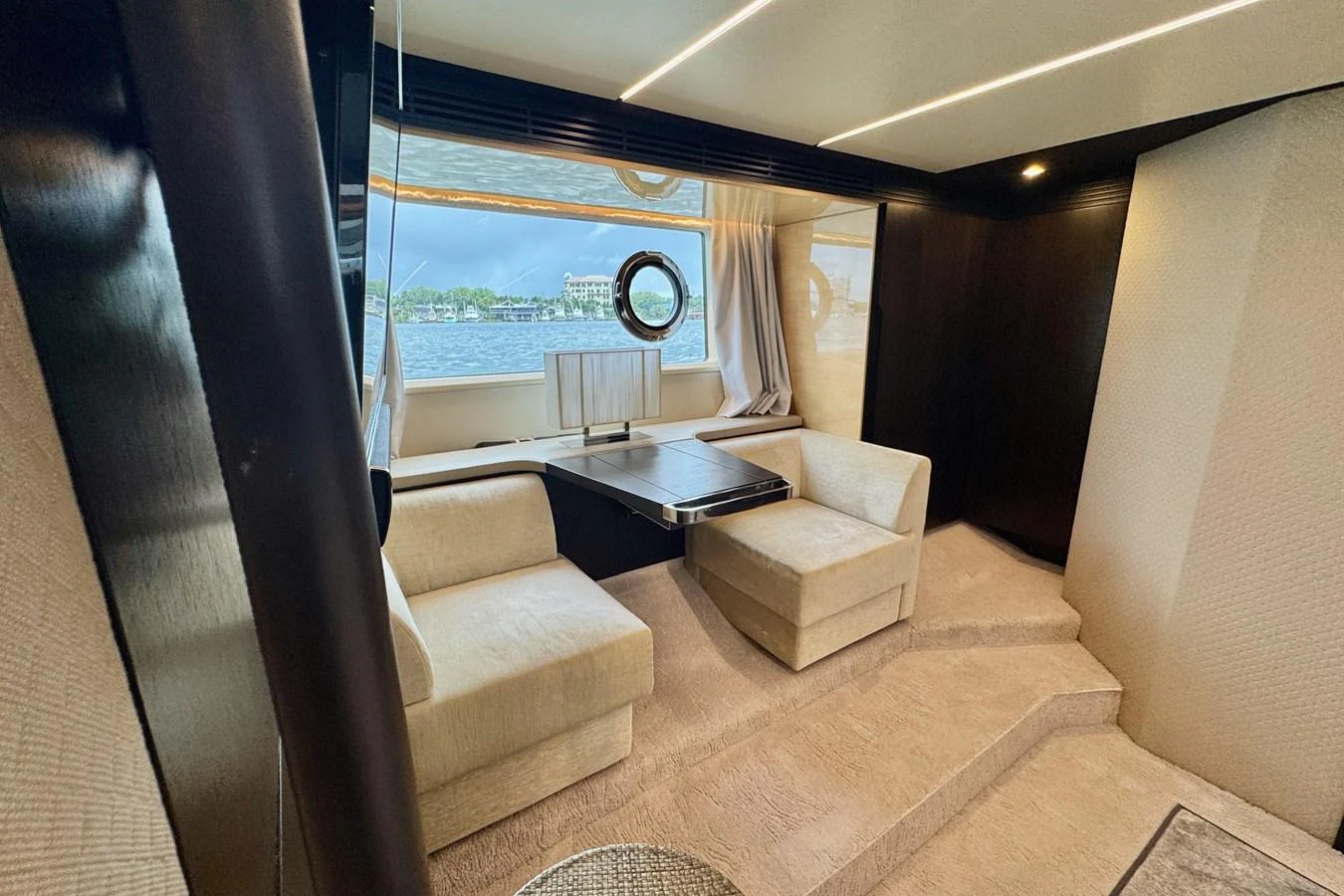 The yacht's interior features a cozy seating area with a table and large windows offering scenic views. aboard KIKI Yacht for Sale