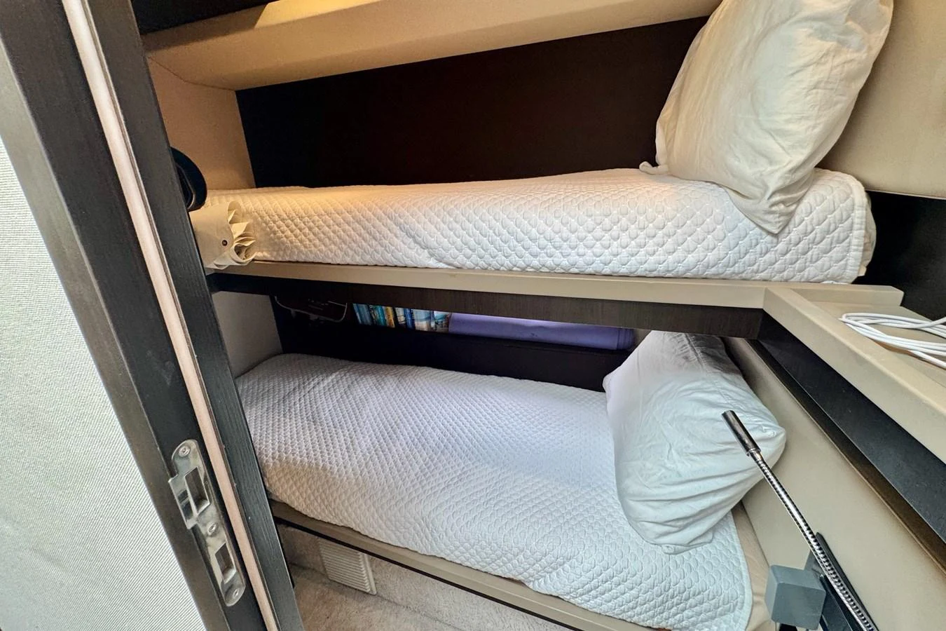 The cozy bunk cabin features two neatly made beds with white linens, providing a comfortable sleeping area. aboard KIKI Yacht for Sale