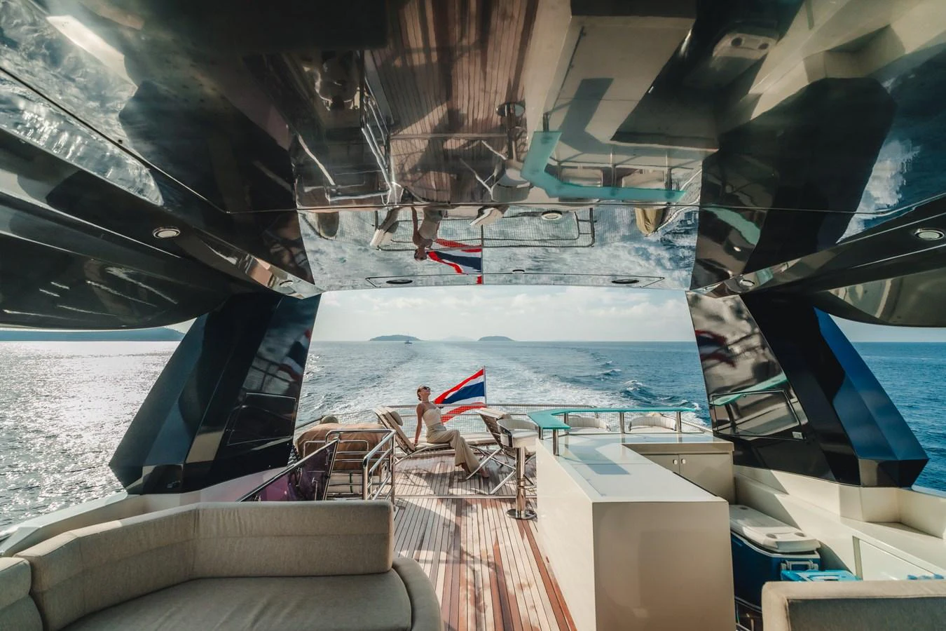 a couple sitting on chairs on a deck overlooking a large body of water aboard MOANA Yacht for Sale