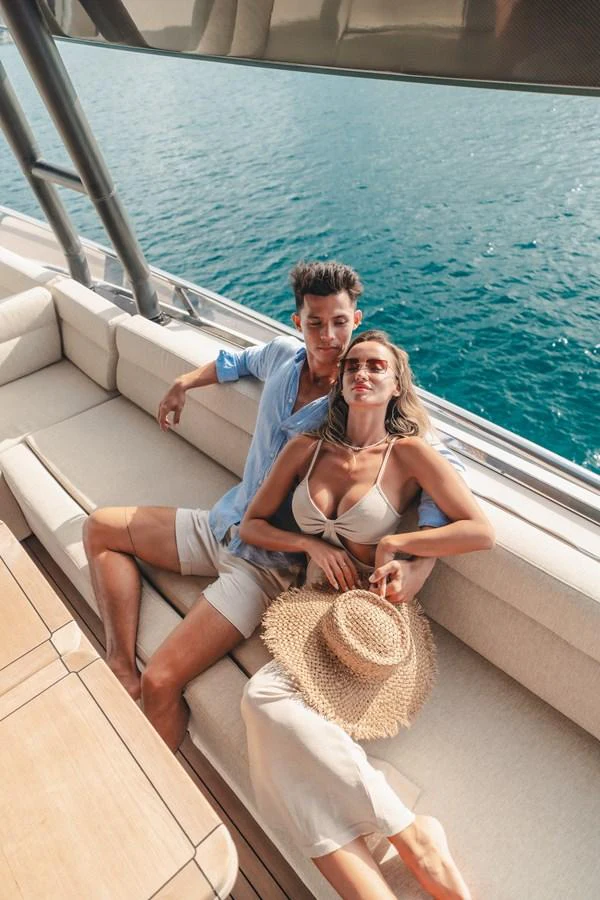 a man and woman sitting on a boat with a woman in the water aboard MOANA Yacht for Sale