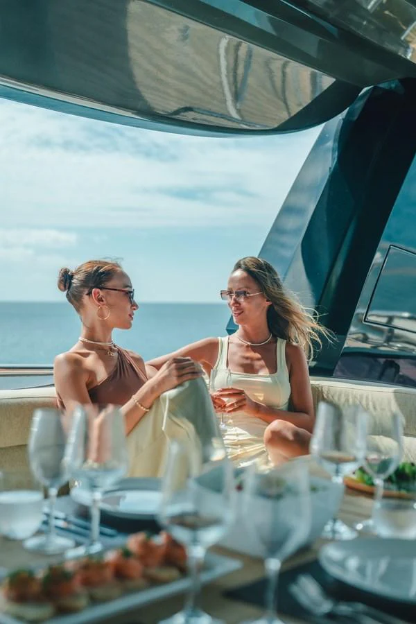 a couple of women sitting at a table with wine glasses aboard MOANA Yacht for Sale