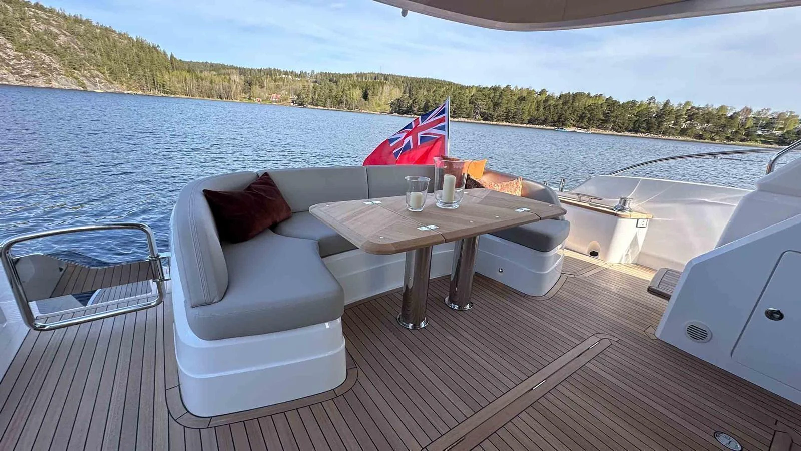 The aft deck features a stylish seating area with a table, perfect for alfresco dining while enjoying scenic views. aboard PRINCESS F65 Yacht for Sale