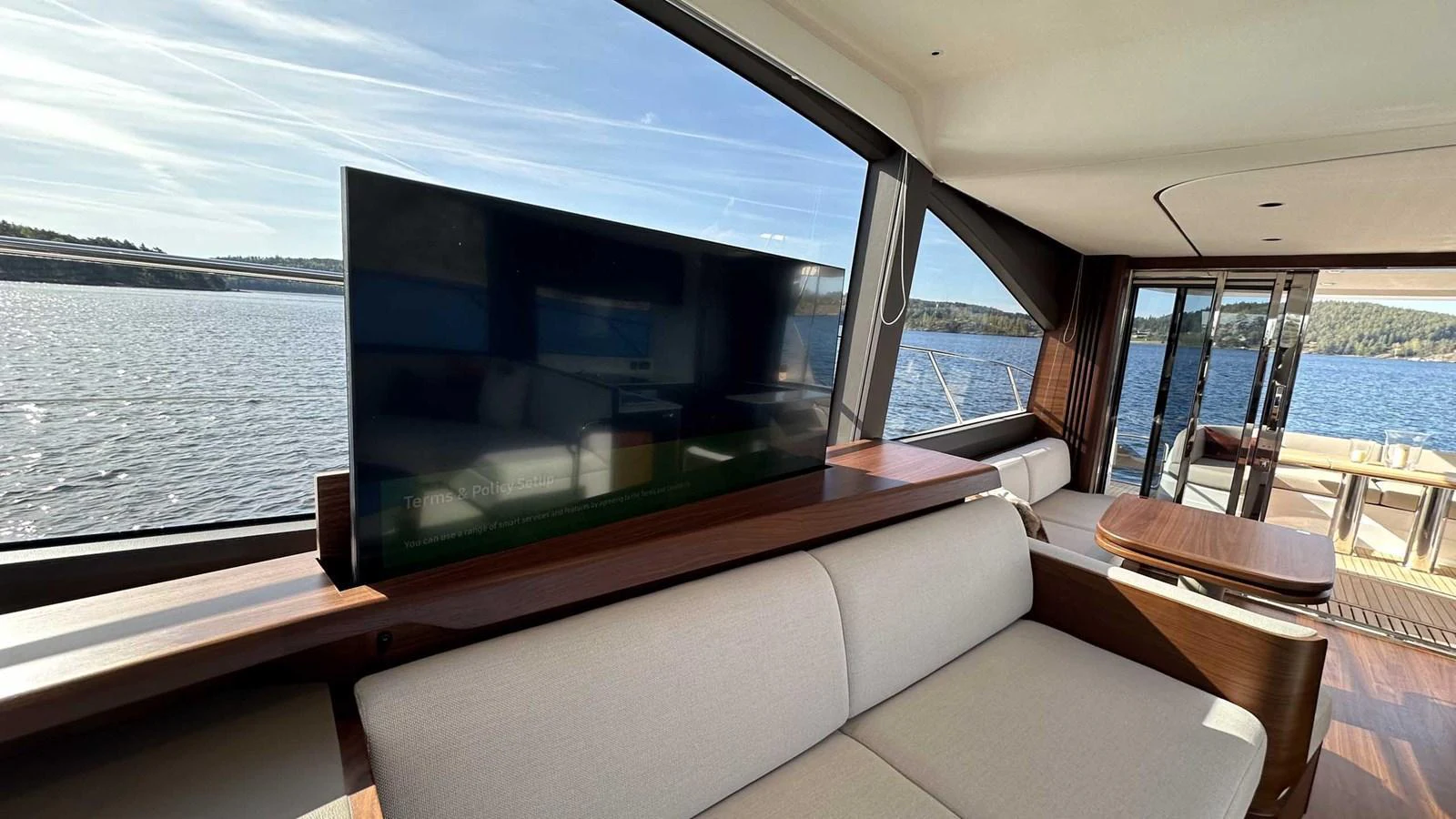 The saloon features a comfortable seating area with a large TV and panoramic windows offering stunning water views. aboard PRINCESS F65 Yacht for Sale