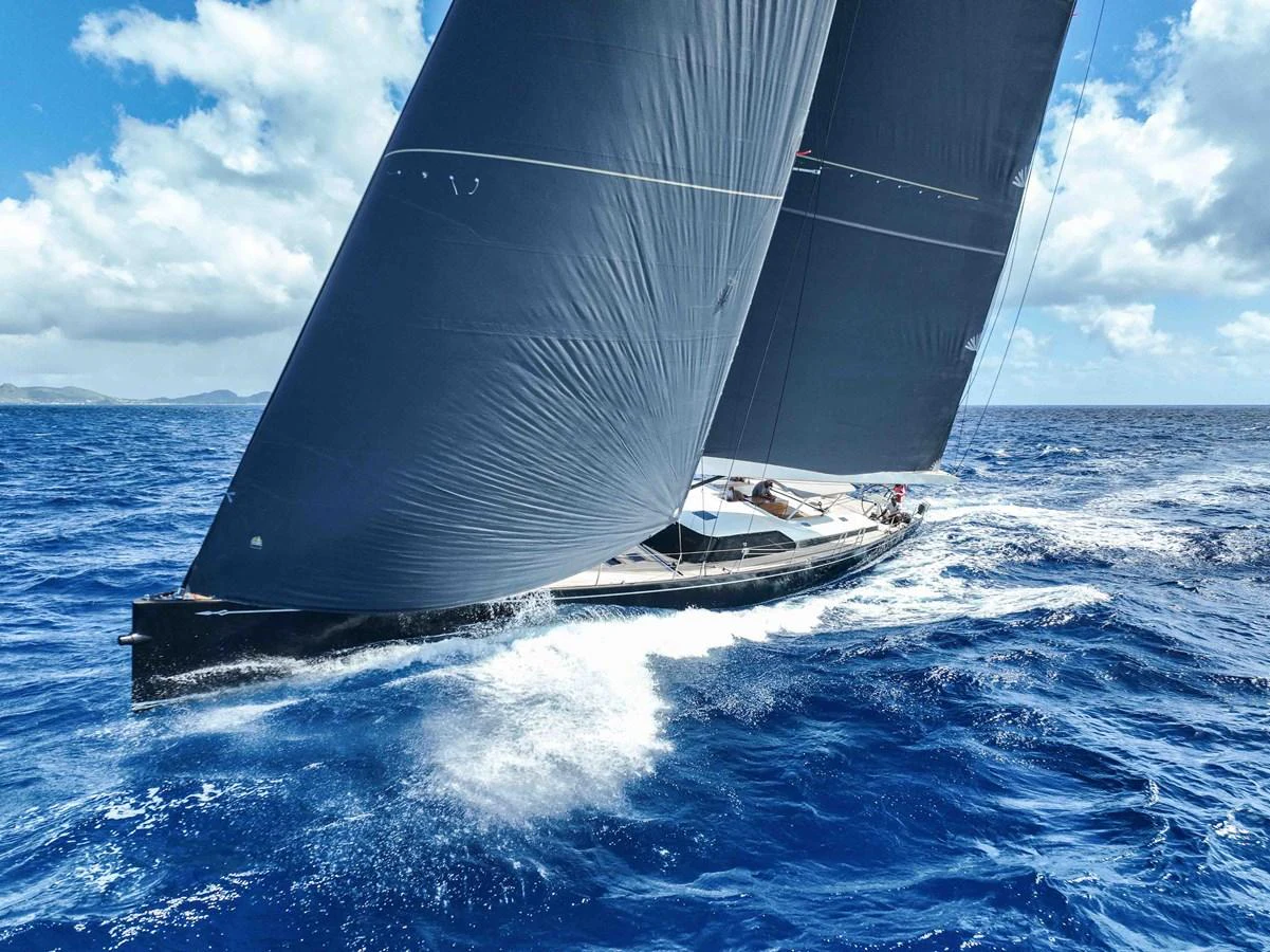 A sleek sailing yacht glides through the vibrant blue ocean under full sail. aboard BLACK PEARL II Yacht for Sale