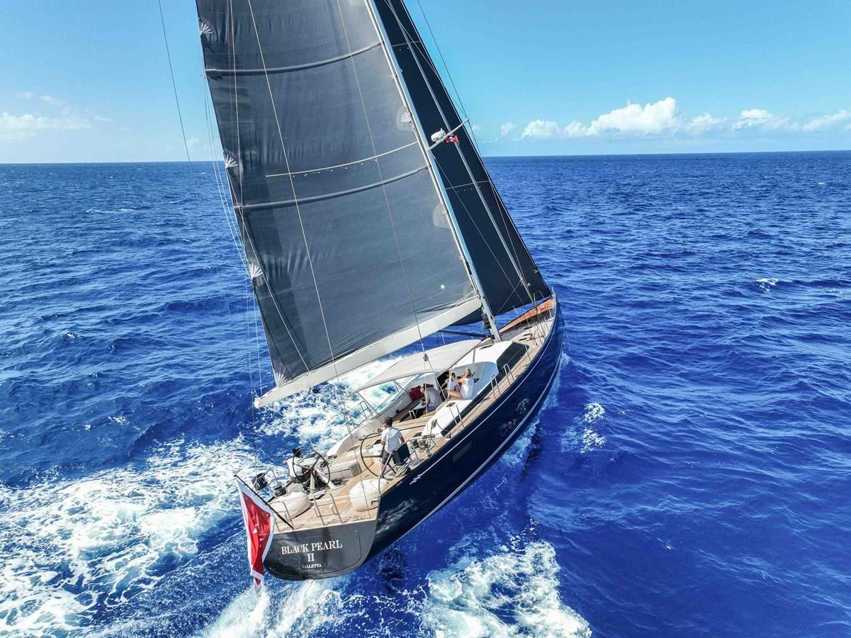A sleek sailing yacht glides gracefully through the open ocean under full sail. aboard BLACK PEARL II Yacht for Sale