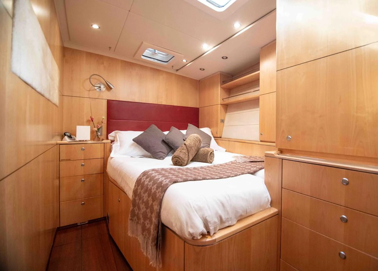 A cozy stateroom featuring a comfortable bed with plush pillows and warm wooden cabinetry. aboard BLACK PEARL II Yacht for Sale