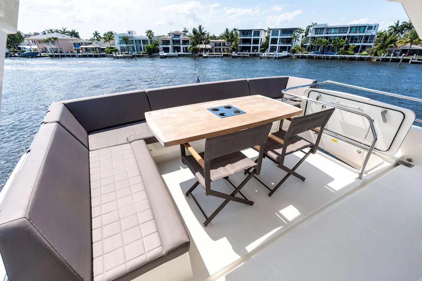 The aft deck features a stylish dining area with a wooden table and comfortable seating, perfect for alfresco meals with a view. aboard JOVE Yacht for Sale