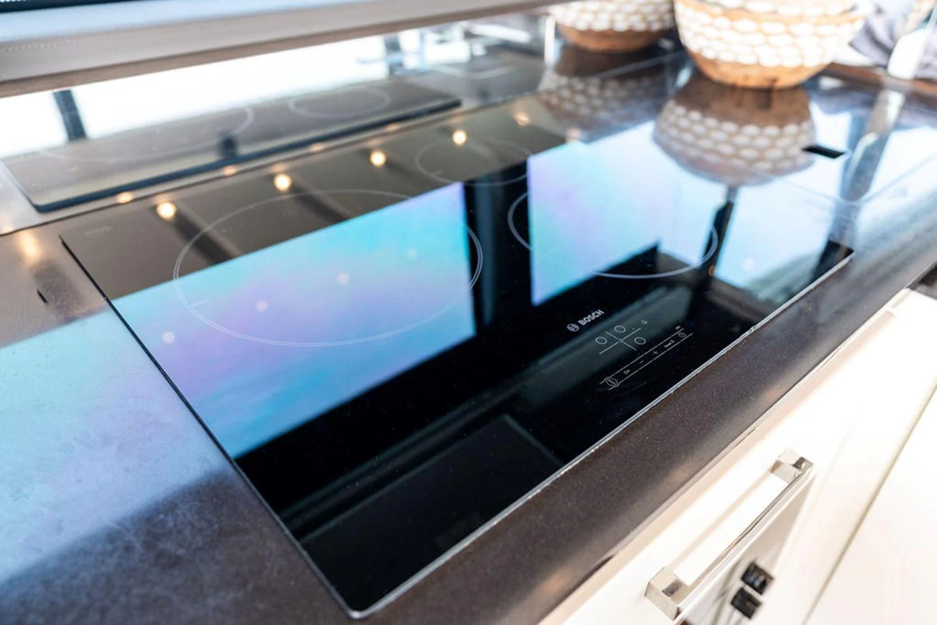 The image showcases a sleek, modern induction cooktop in the yacht's galley. aboard JOVE Yacht for Sale