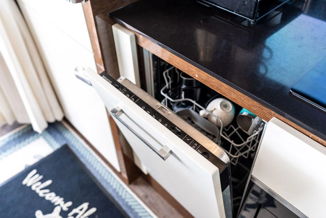 The image showcases a modern galley with an open dishwasher, highlighting the yacht's practical amenities. aboard JOVE Yacht for Sale