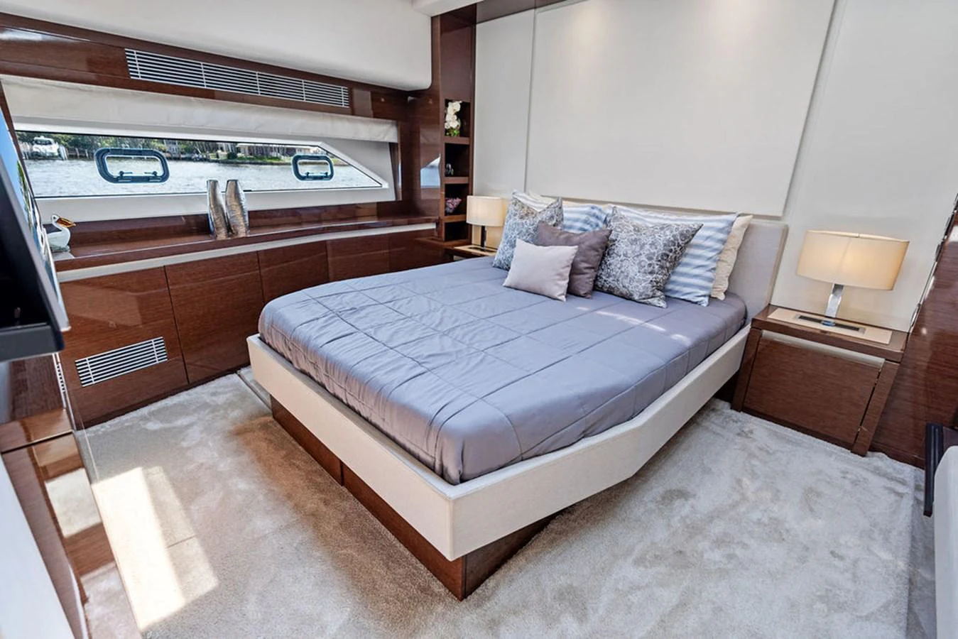 The stateroom features a luxurious bed with elegant bedding and ample natural light from the large windows. aboard JOVE Yacht for Sale