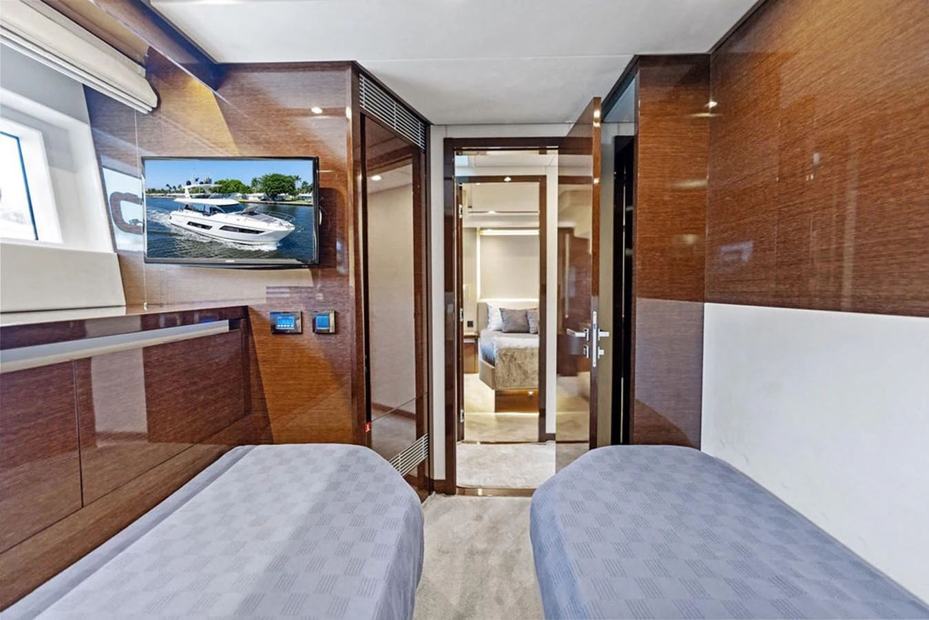 The guest stateroom features twin beds, modern wood paneling, and a view into the adjoining room. aboard JOVE Yacht for Sale