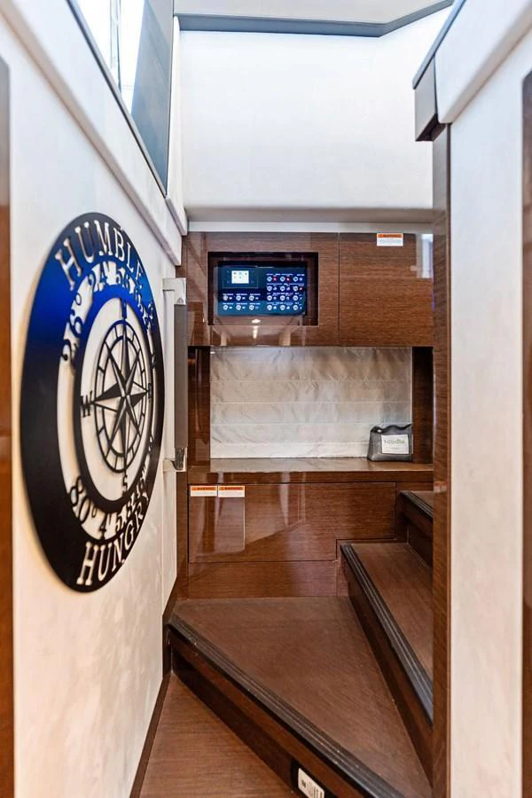 A stylish interior stairway with wooden steps and a nautical-themed wall decoration. aboard JOVE Yacht for Sale