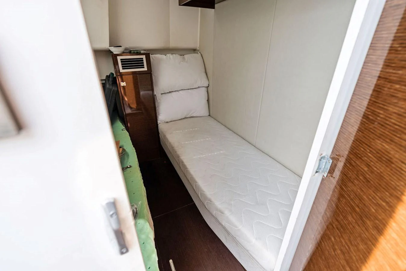 A cozy cabin featuring a single bed with white bedding and a wooden accent wall. aboard JOVE Yacht for Sale