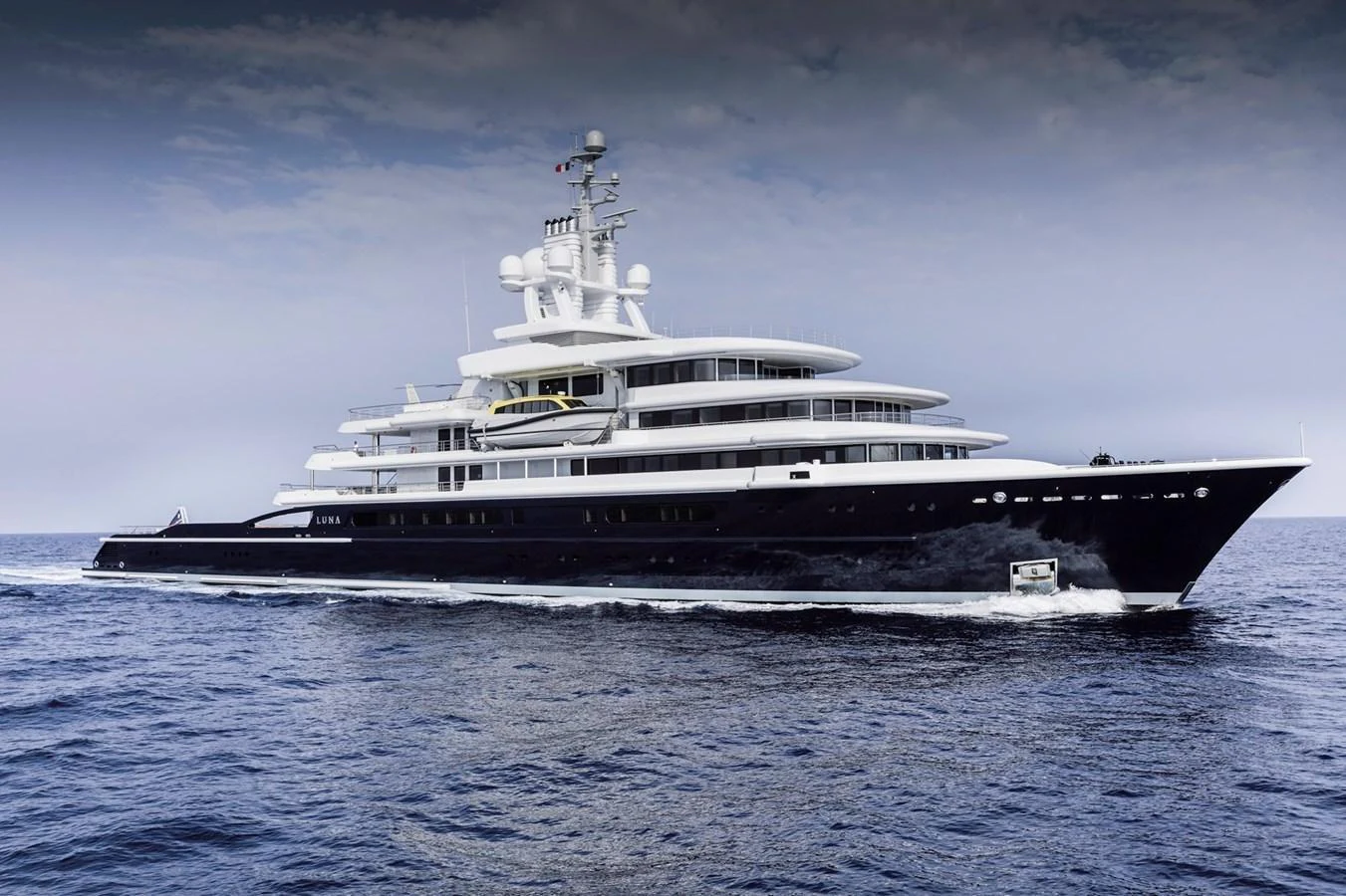 A sleek and modern yacht cruising on calm waters under a cloudy sky. aboard LUNA Yacht for Sale