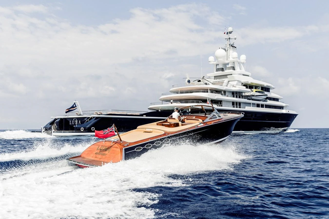 A luxurious yacht cruises on the open sea accompanied by a sleek tender boat. aboard LUNA Yacht for Sale