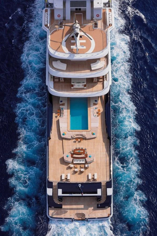 An aerial view of a luxurious yacht showcasing its expansive decks and inviting pool as it cruises through the water. aboard LUNA Yacht for Sale