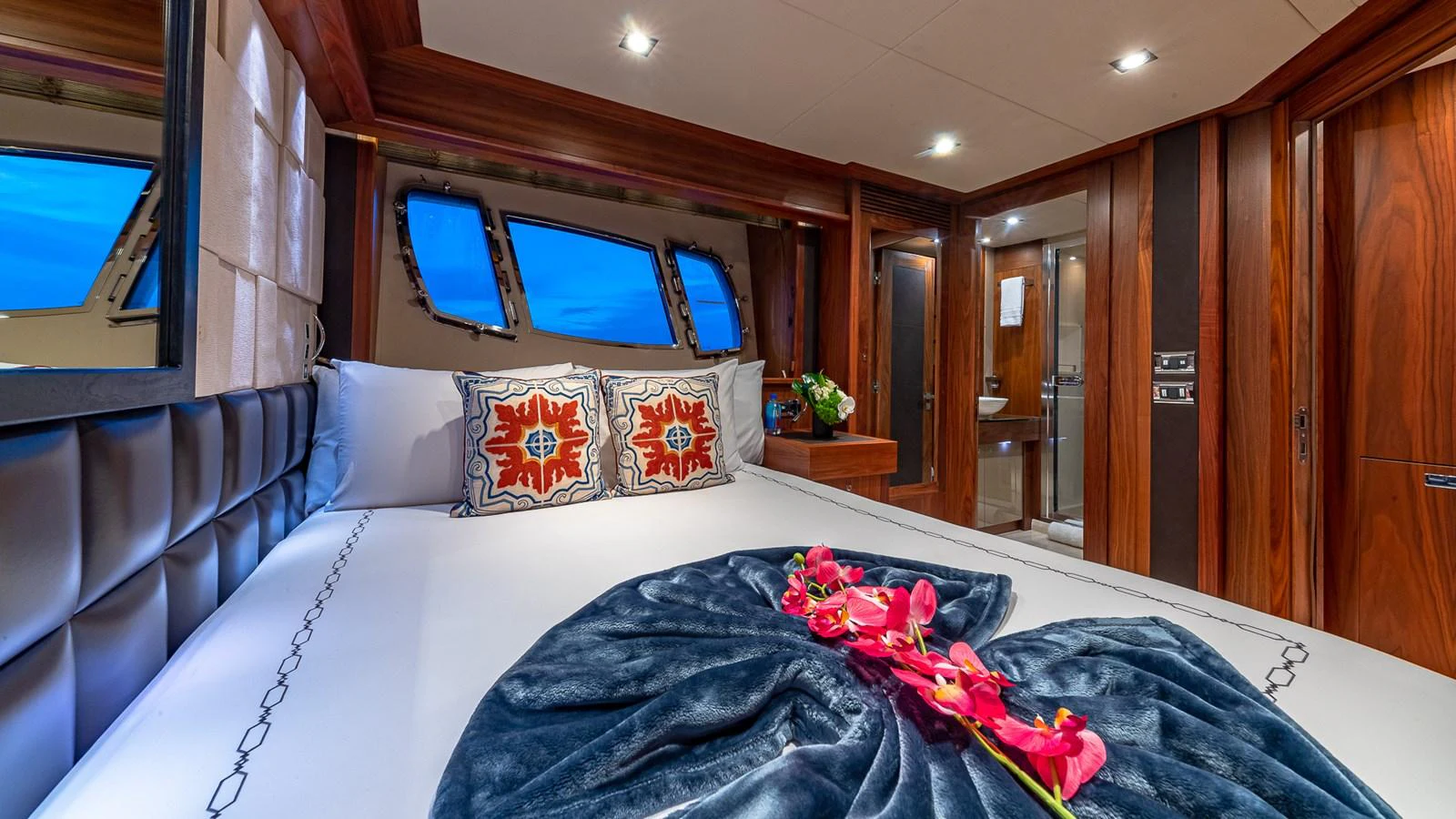 a bed with a blue sheet and pillows aboard EMRYS Yacht for Sale