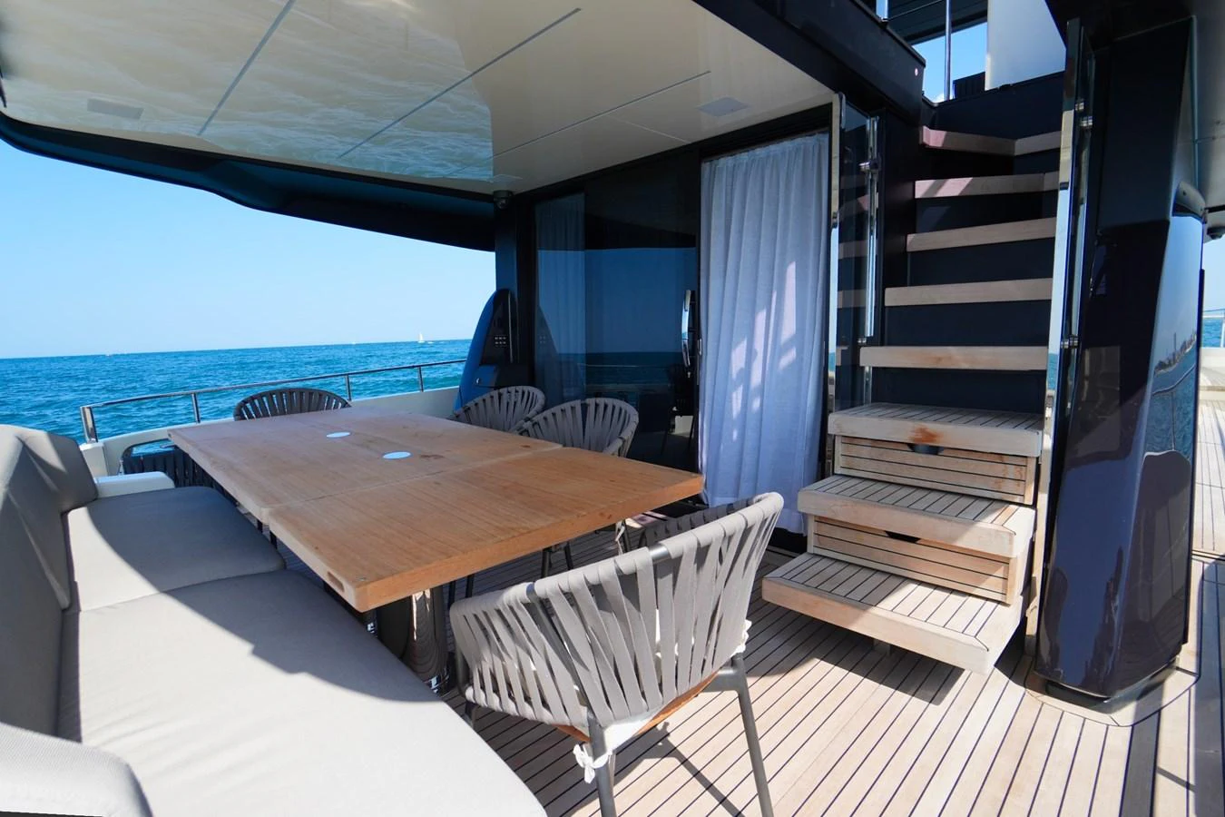 The aft deck features a spacious dining area with a wooden table and comfortable seating, perfect for alfresco meals with a view of the sea. aboard AMY Yacht for Sale