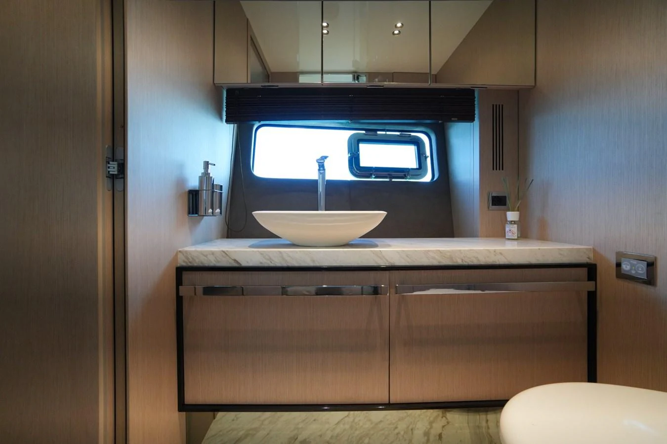 A modern yacht bathroom with a sleek sink and a window providing natural light. aboard AMY Yacht for Sale