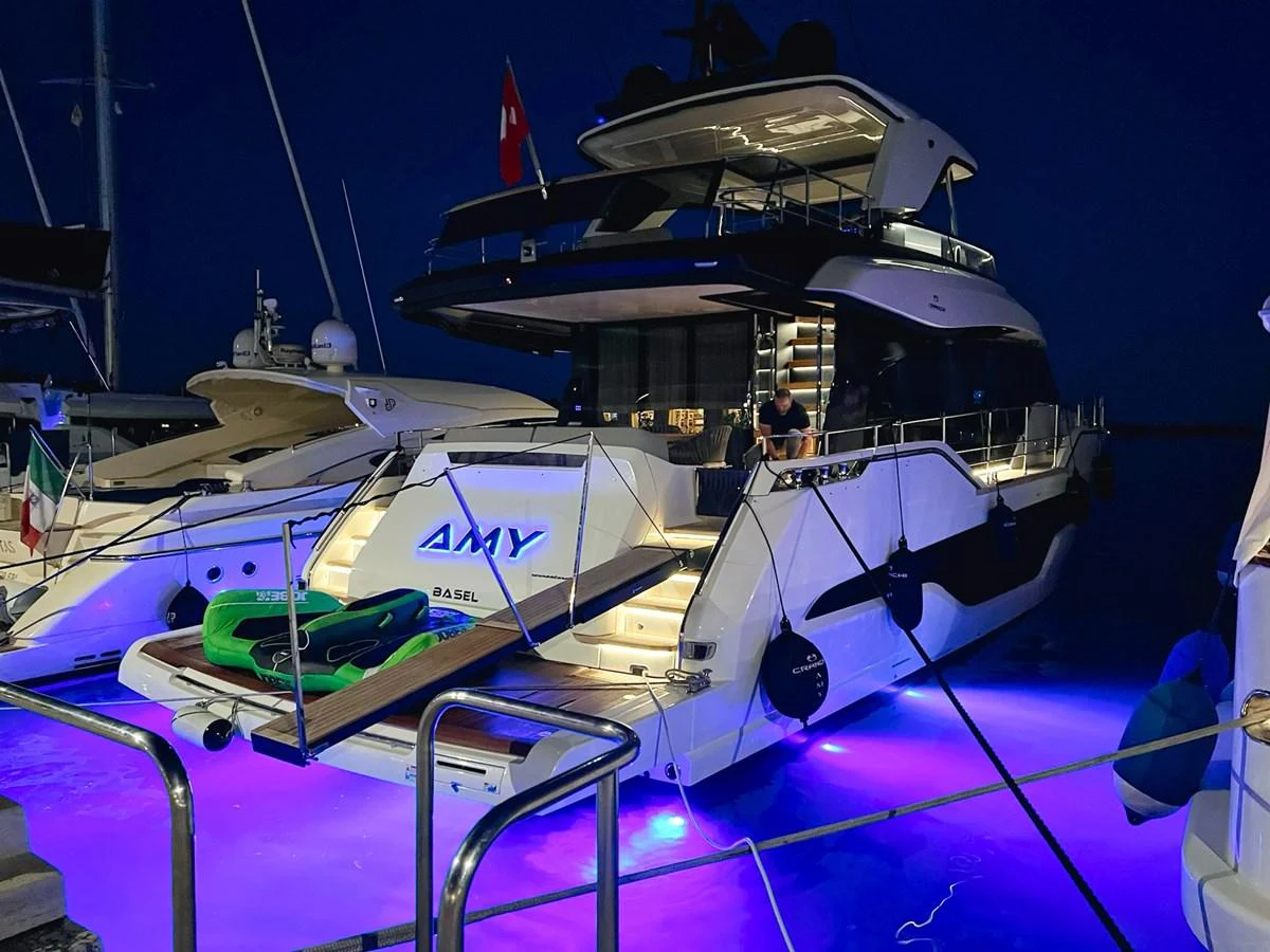 The yacht is docked at night, illuminated by vibrant underwater lights, creating a captivating ambiance. aboard AMY Yacht for Sale