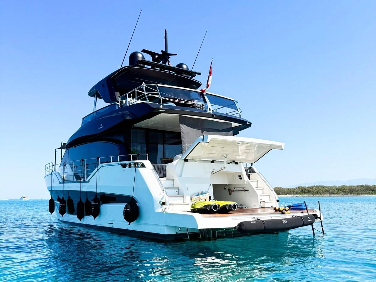 A luxurious yacht anchored in clear blue waters, showcasing its spacious aft deck and sleek design. aboard AMY Yacht for Sale