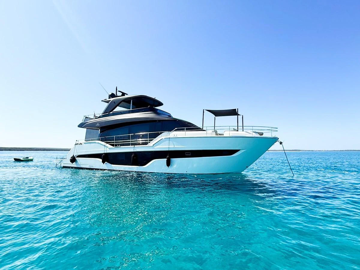 A sleek and modern yacht floats gracefully on crystal-clear waters under a bright blue sky. aboard AMY Yacht for Sale