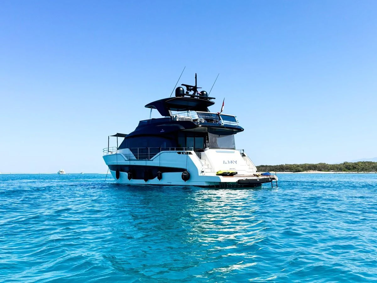 A sleek yacht cruises on clear blue waters under a bright sky. aboard AMY Yacht for Sale