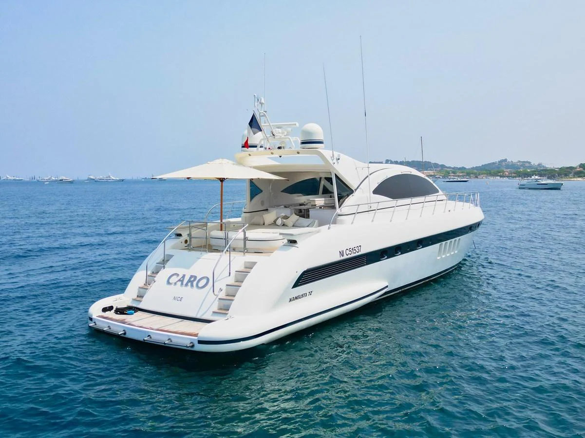 A sleek and modern yacht is anchored on calm waters, showcasing its elegant aft deck and streamlined design. aboard CARO Yacht for Sale