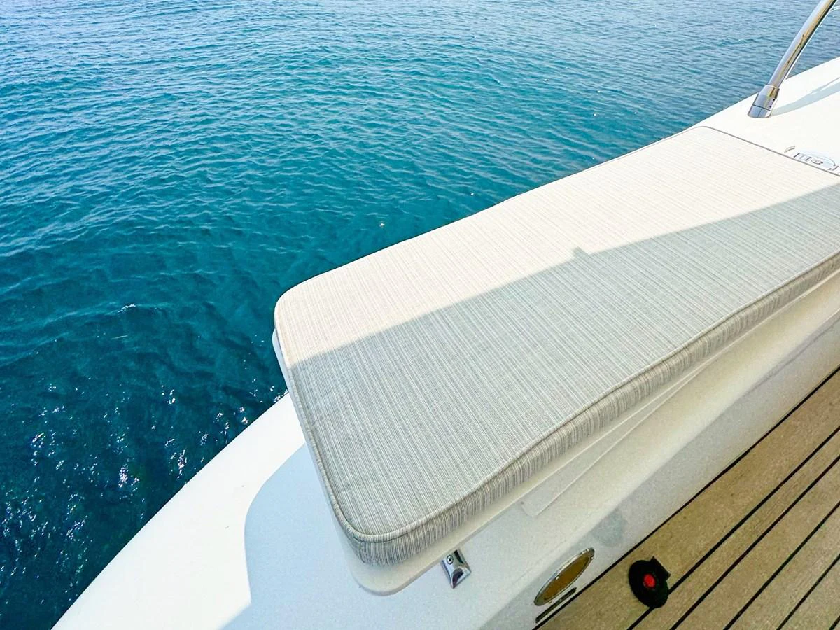 A close-up view of a cushioned sun pad on the deck of a yacht, overlooking the serene blue water. aboard CARO Yacht for Sale